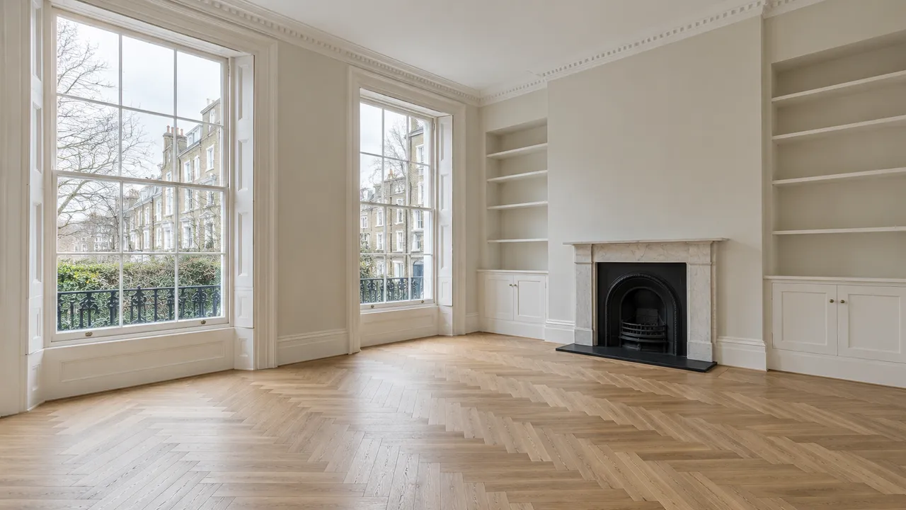 An empty London rental living room with clean oak flooring and sash windows
